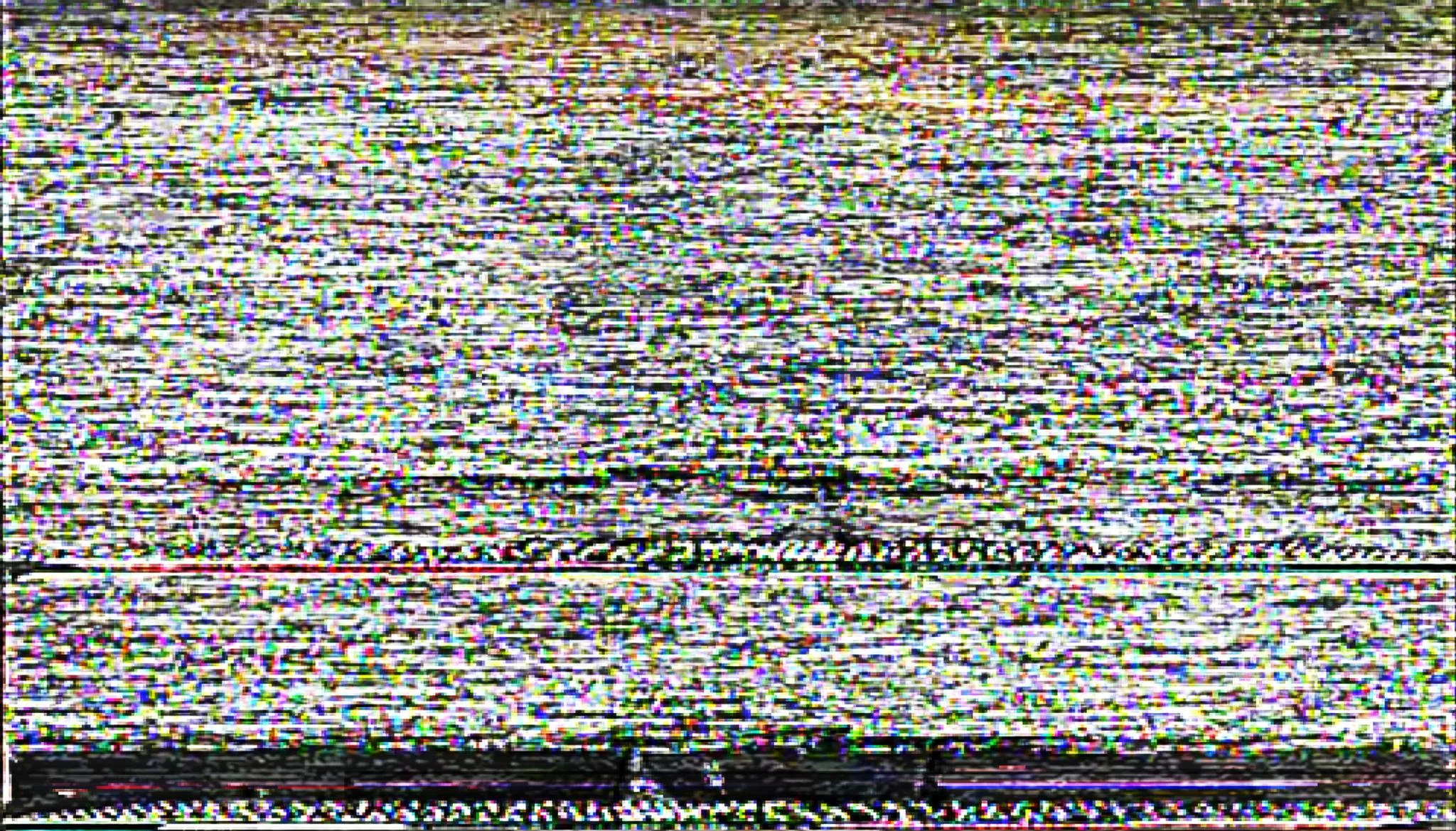 Failing computer monitor displaying heavy signal noise and snow across the screen