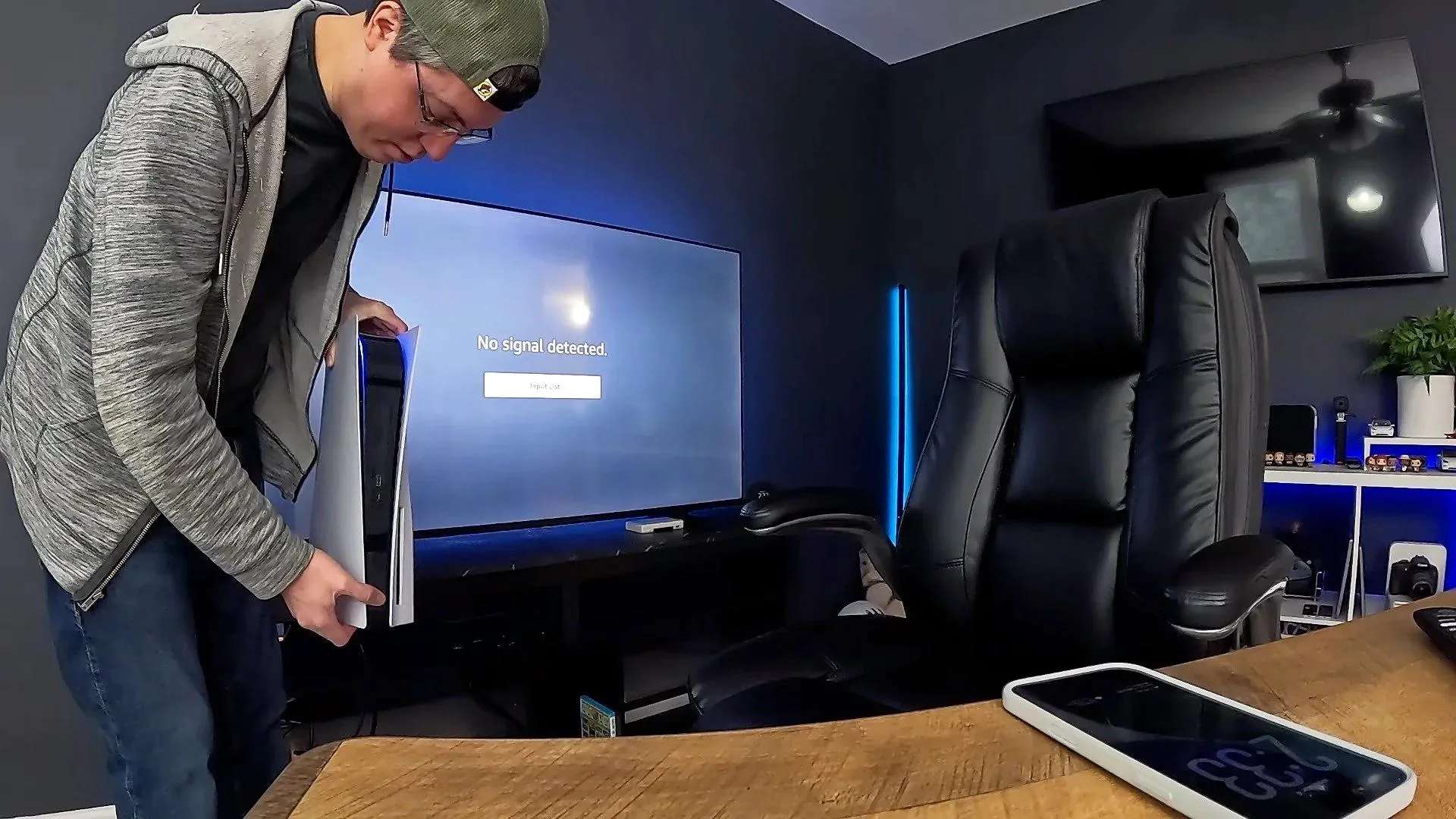 Person holding a PlayStation 5 in front of a TV displaying No signal detected, troubleshooting an HDMI connection issue