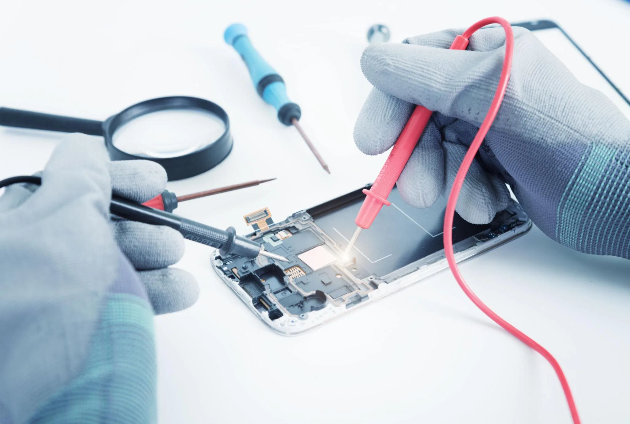 Multimeter and bench tools verifying a replacement smartphone screen before final assembly